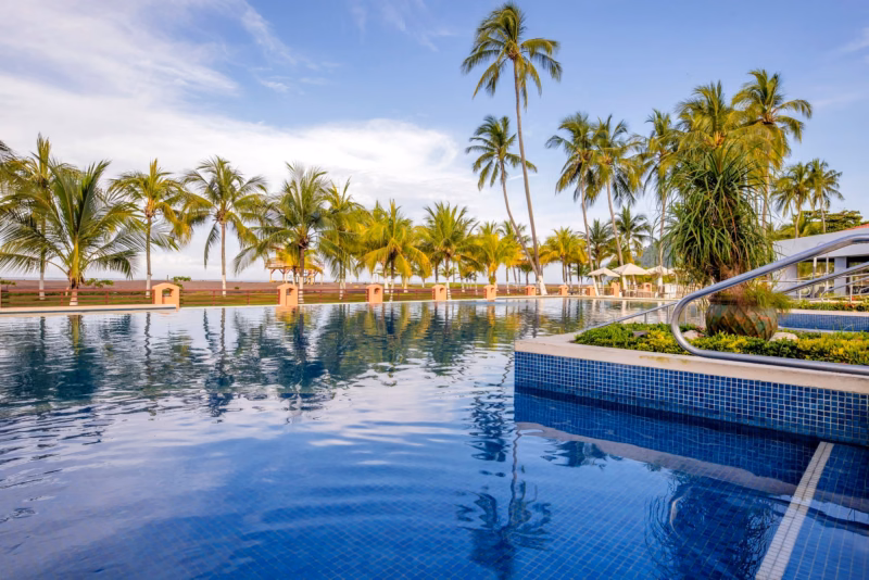 Piscina del Best Western Jacó con palmeras frente a la playa