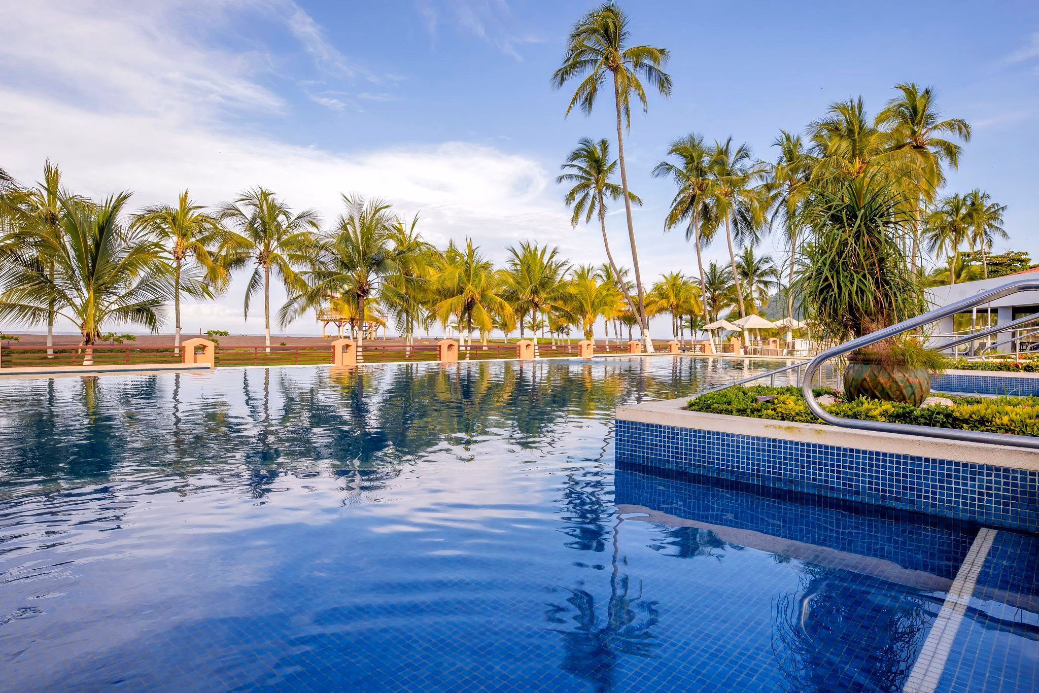 Piscina del Best Western Jacó con palmeras frente a la playa